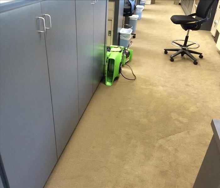 two green devices blowing air in an office pathway